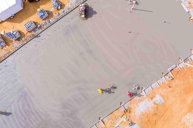 Worker preparing base and reinforcement for concrete patio installation, showing early construction phase