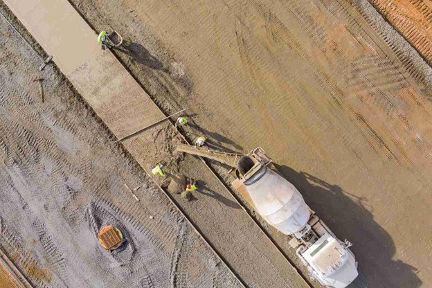 Concrete slab being poured and finished in hot weather conditions on a construction site in Texas